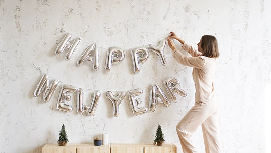 Femme accrochant une banderole bonne année sur un mur blanc pour symboliser les bonnes résolutions à prendre