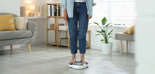 Femme se pesant sur une balance à la maison, illustrant la ménopause et la prise de poids
